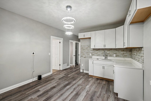 kitchen featuring dark wood-type flooring, white cabinets, sink, decorative backsplash, and decorative light fixtures