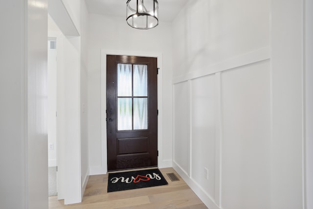 doorway featuring a notable chandelier and light hardwood / wood-style floors