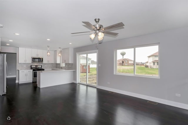 kitchen with appliances with stainless steel finishes, white cabinetry, backsplash, kitchen peninsula, and ceiling fan