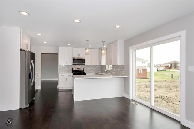 kitchen featuring white cabinets, kitchen peninsula, decorative light fixtures, stainless steel appliances, and dark hardwood / wood-style floors