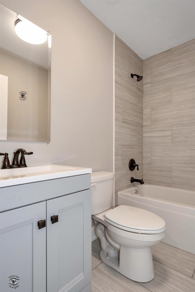 full bathroom with tiled shower / bath, vanity, and toilet