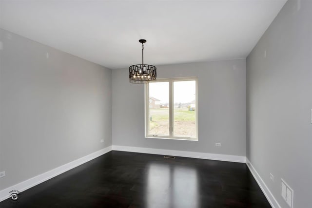 unfurnished room with a chandelier