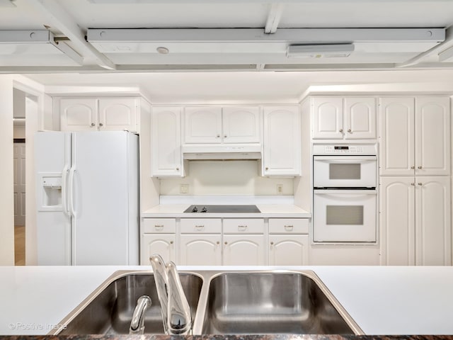 kitchen with white appliances, white cabinetry, and sink