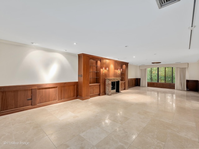 unfurnished living room featuring wooden walls, a fireplace, and crown molding