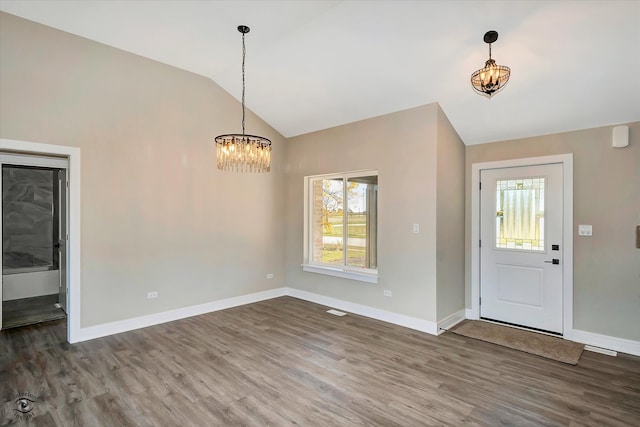 entrance foyer with lofted ceiling, wood-type flooring, and an inviting chandelier