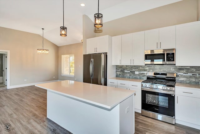 kitchen with a center island, stainless steel appliances, vaulted ceiling, pendant lighting, and white cabinets