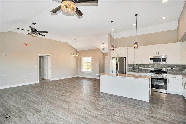 kitchen with white cabinetry, stainless steel appliances, wood-type flooring, and a kitchen island