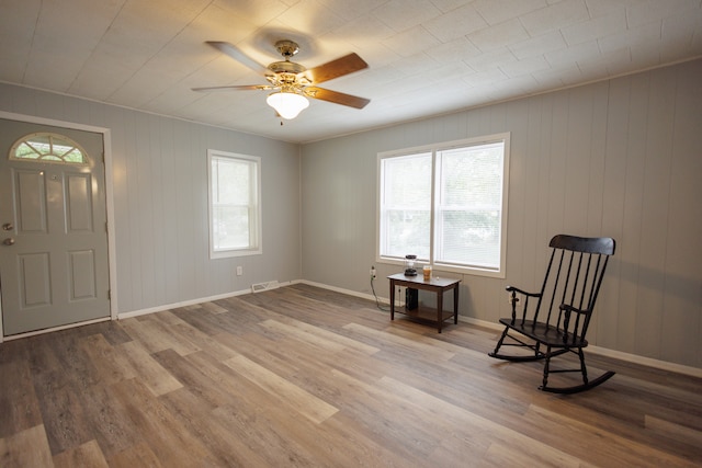 unfurnished room with ceiling fan, wooden walls, and hardwood / wood-style floors