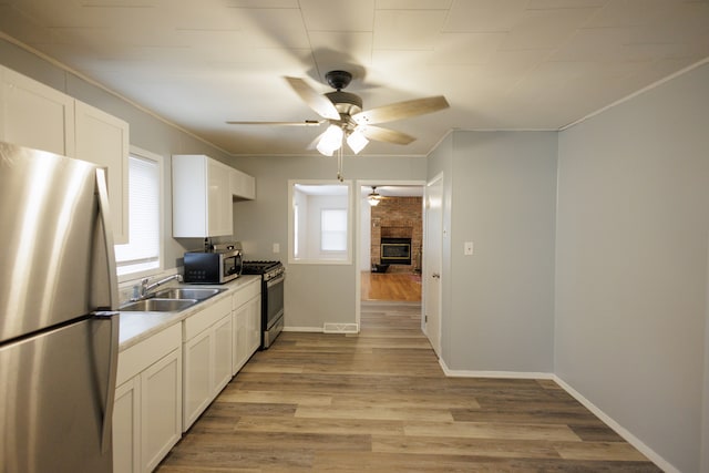 kitchen with stainless steel appliances, ceiling fan, a healthy amount of sunlight, and sink