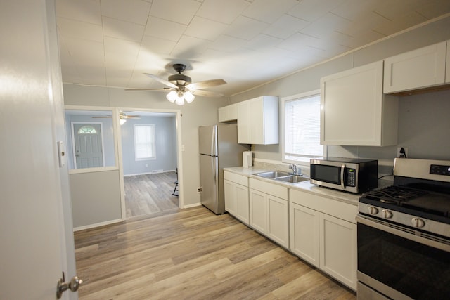 kitchen featuring light hardwood / wood-style floors, sink, white cabinets, stainless steel appliances, and ceiling fan