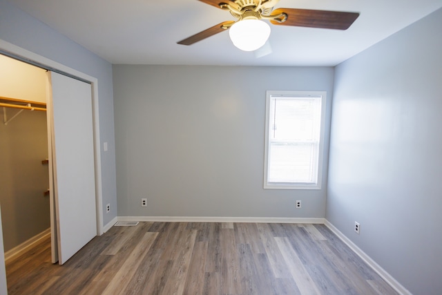 unfurnished bedroom featuring ceiling fan, hardwood / wood-style flooring, and a closet