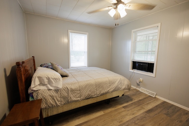 bedroom with wood-type flooring, cooling unit, ceiling fan, and crown molding