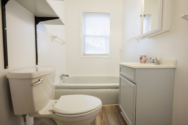 bathroom with a bath, hardwood / wood-style floors, vanity, and toilet