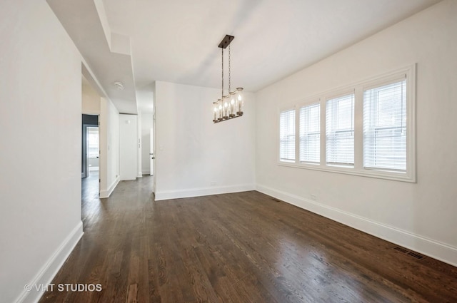 unfurnished dining area with dark hardwood / wood-style flooring and an inviting chandelier