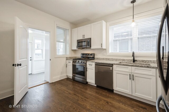 kitchen featuring stainless steel appliances, sink, decorative light fixtures, white cabinets, and dark hardwood / wood-style floors