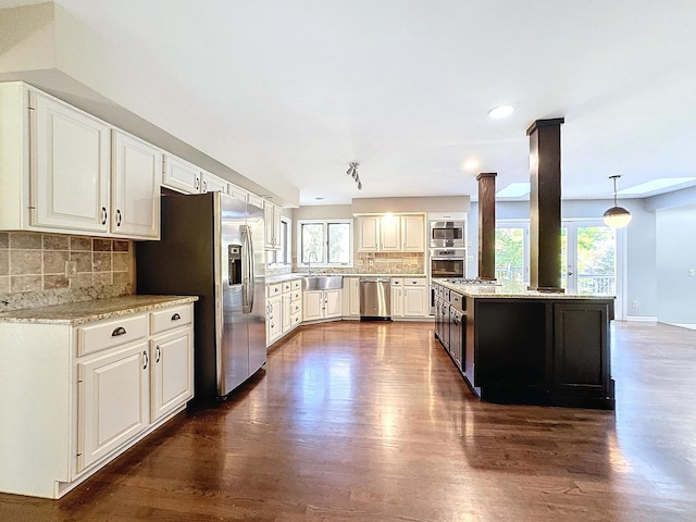 kitchen with dark hardwood / wood-style floors, hanging light fixtures, sink, white cabinets, and appliances with stainless steel finishes