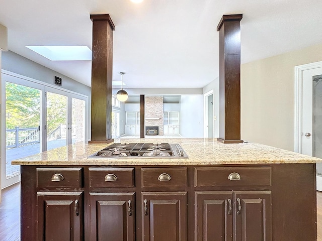 kitchen featuring stainless steel gas cooktop, hanging light fixtures, dark brown cabinetry, a skylight, and dark hardwood / wood-style flooring