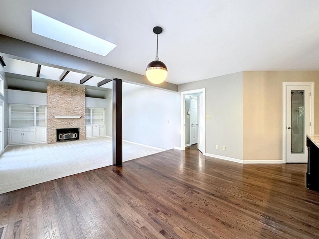 unfurnished living room with a fireplace, built in features, a skylight, and dark hardwood / wood-style floors