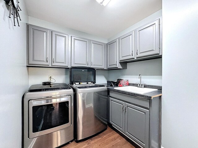 washroom with sink, cabinets, light wood-type flooring, and washer and clothes dryer