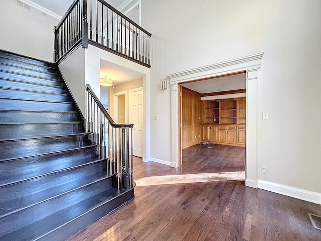 stairway with crown molding, built in features, and hardwood / wood-style floors