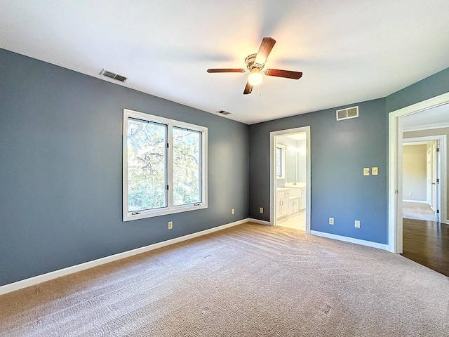 unfurnished bedroom with ensuite bath, light colored carpet, and ceiling fan