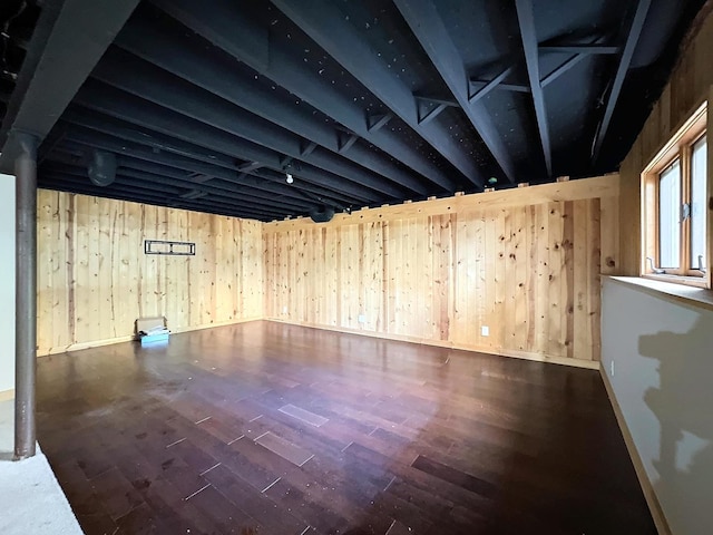 basement featuring dark wood-type flooring and wood walls