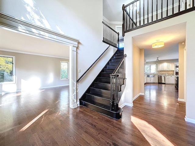 staircase with ornamental molding, a high ceiling, and hardwood / wood-style flooring