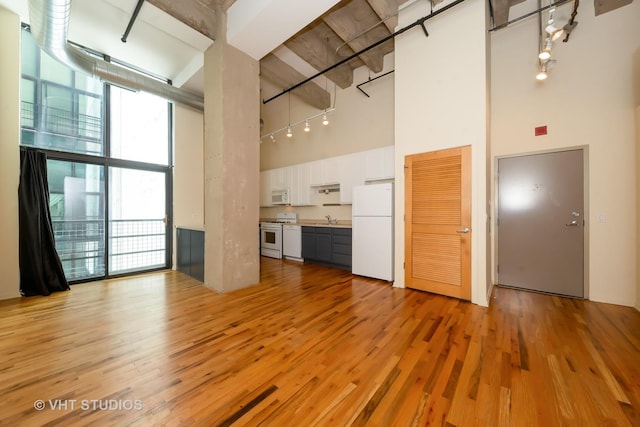 1645 W Ogden Ave Unit 434, Chicago, IL 60612 - unfurnished living room featuring a high ceiling, a sink, light wood-style flooring, floor to ceiling windows, and beam ceiling