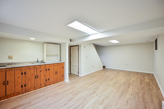 interior space featuring light wood-style floors, baseboards, light countertops, and brown cabinetry