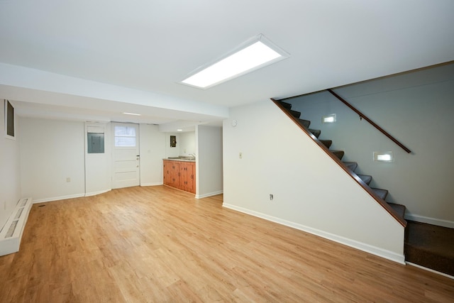 basement with stairs, electric panel, light wood-style flooring, and baseboards