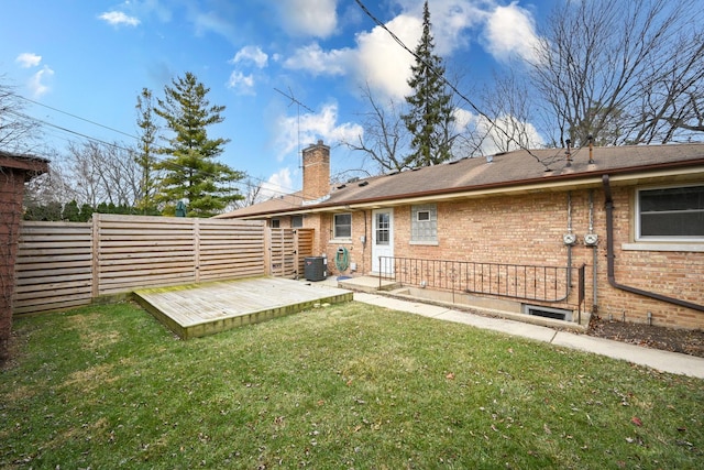 back of house with a deck, a yard, brick siding, and fence