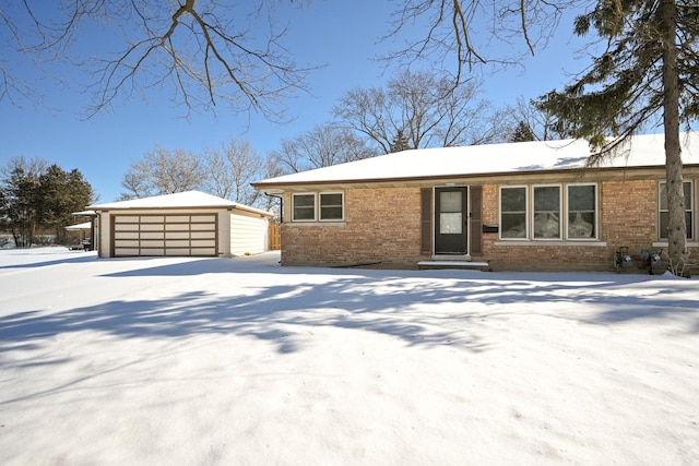 view of front of home featuring a garage, brick siding, and an outbuilding