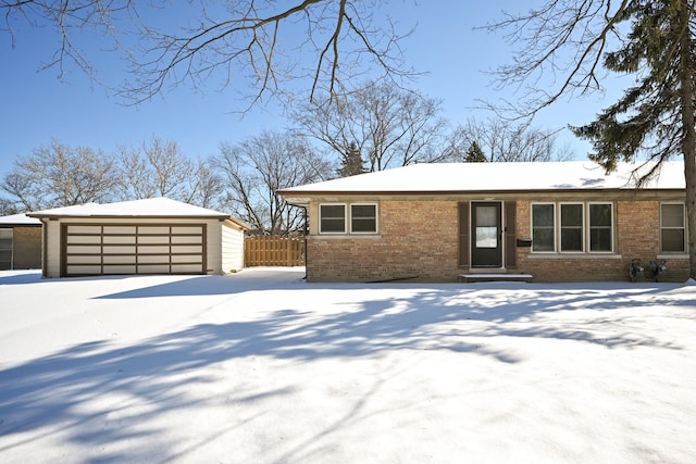 view of front of home featuring brick siding, a detached garage, fence, and an outbuilding