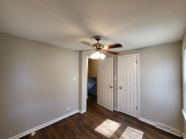 unfurnished bedroom featuring ceiling fan, a closet, and dark wood-type flooring