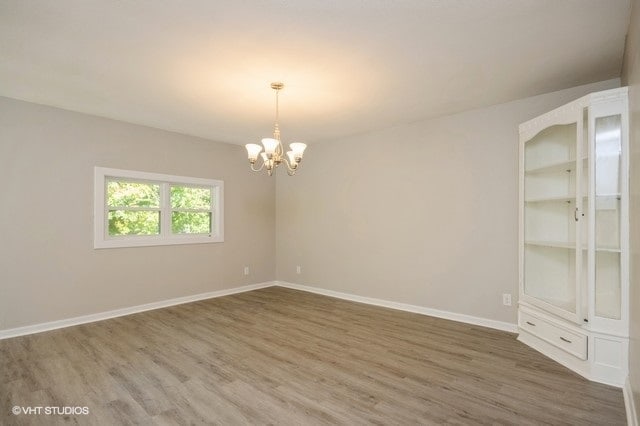 empty room with an inviting chandelier and dark hardwood / wood-style floors