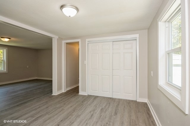 unfurnished bedroom with a closet, hardwood / wood-style floors, and multiple windows