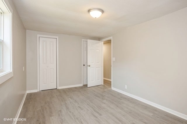 unfurnished bedroom with light wood-type flooring and a closet