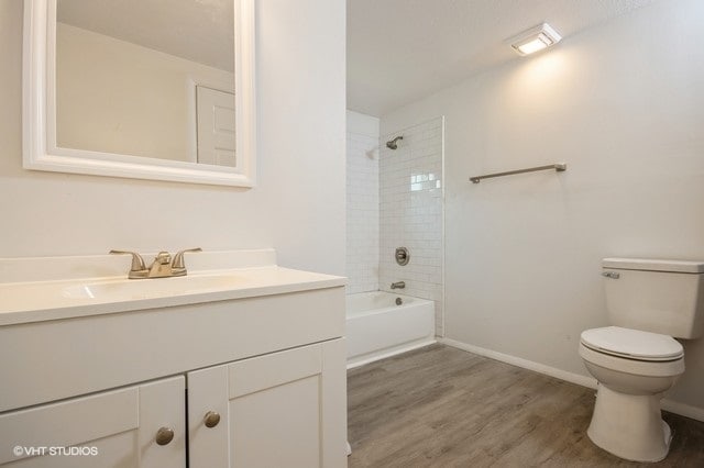 full bathroom featuring tiled shower / bath combo, vanity, toilet, and hardwood / wood-style floors