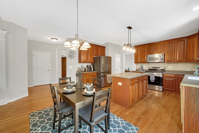 kitchen with light hardwood / wood-style flooring, appliances with stainless steel finishes, hanging light fixtures, and a center island