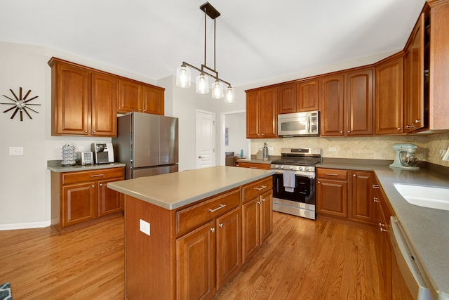 kitchen with hanging light fixtures, a kitchen island, backsplash, appliances with stainless steel finishes, and light hardwood / wood-style floors