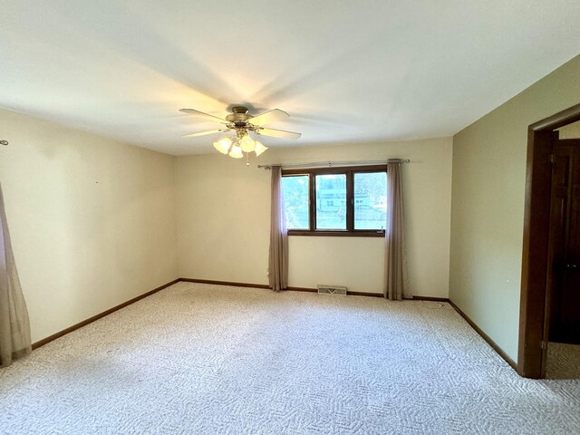 unfurnished room with baseboards, ceiling fan, visible vents, and light colored carpet