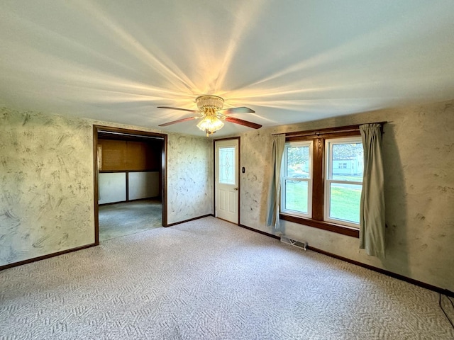 interior space featuring baseboards, carpet floors, visible vents, and a ceiling fan