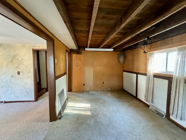 carpeted empty room featuring wood ceiling, beamed ceiling, and a fireplace