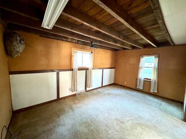 unfurnished room featuring wood ceiling, beam ceiling, carpet, and a healthy amount of sunlight