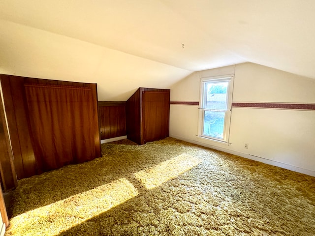 bonus room featuring wooden walls, carpet flooring, and vaulted ceiling