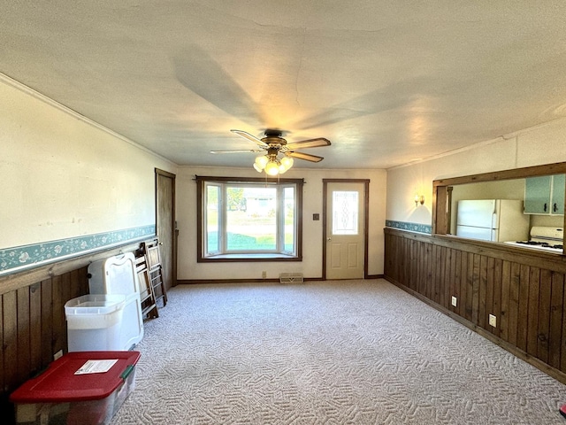 living room featuring a wainscoted wall, light carpet, wooden walls, and ceiling fan