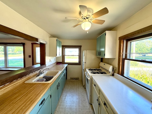 kitchen with ceiling fan, white range with gas stovetop, sink, and a wealth of natural light