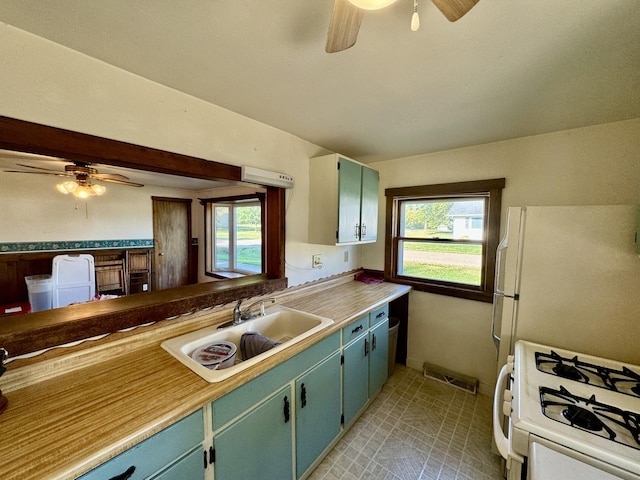kitchen featuring light countertops, a sink, a ceiling fan, white appliances, and visible vents