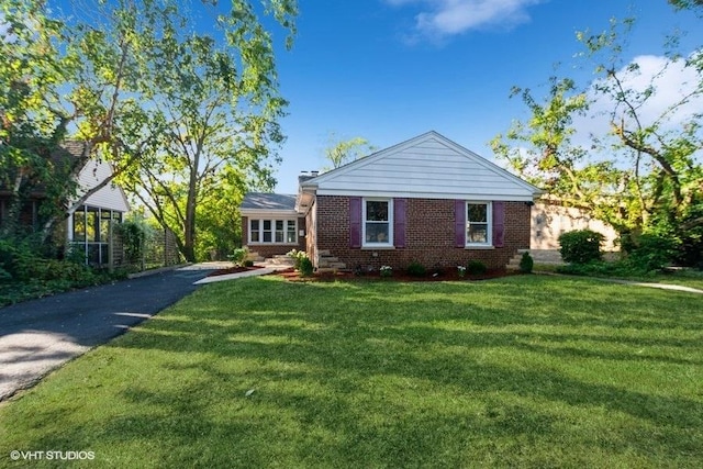 view of front facade with brick siding and a front yard