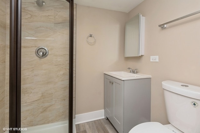 bathroom featuring a tile shower, vanity, hardwood / wood-style floors, and toilet